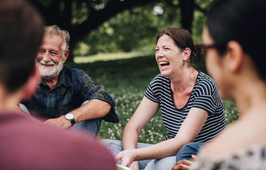 group of people sitting together in a park laughing