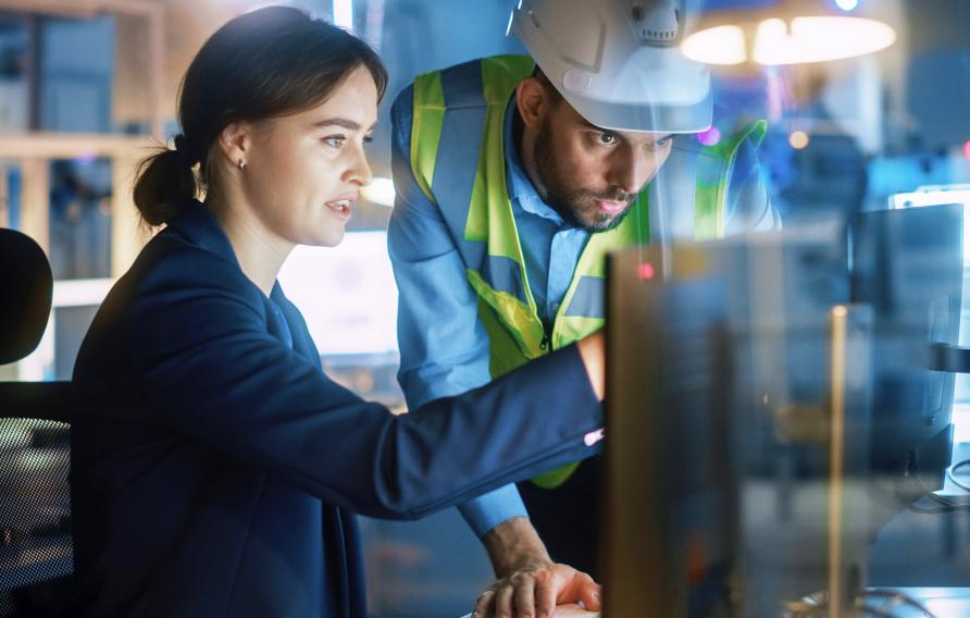 Woman and man in PPE look onto a computer