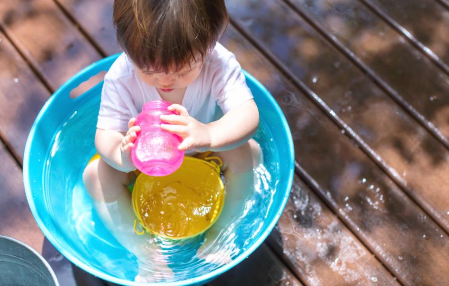 Toddler in a kiddie pool drinking out of a pink sippy cup