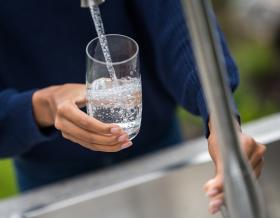 Woman's hands filling glass with water stock photo