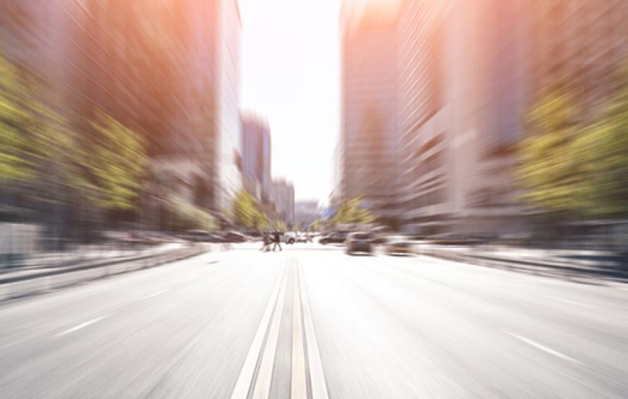 Blurred image of a road facing toward a downtown with office buildings