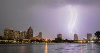 Cityscape with purple overcast sky and lightning striking over water