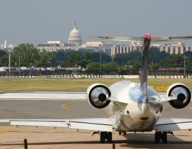 Airplane landing on a runway with Washington, DC skyline, including White House, in background