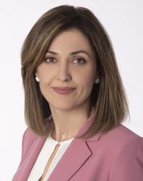 Medium skinned woman with brown short hair in a pink suit coat and white blouse